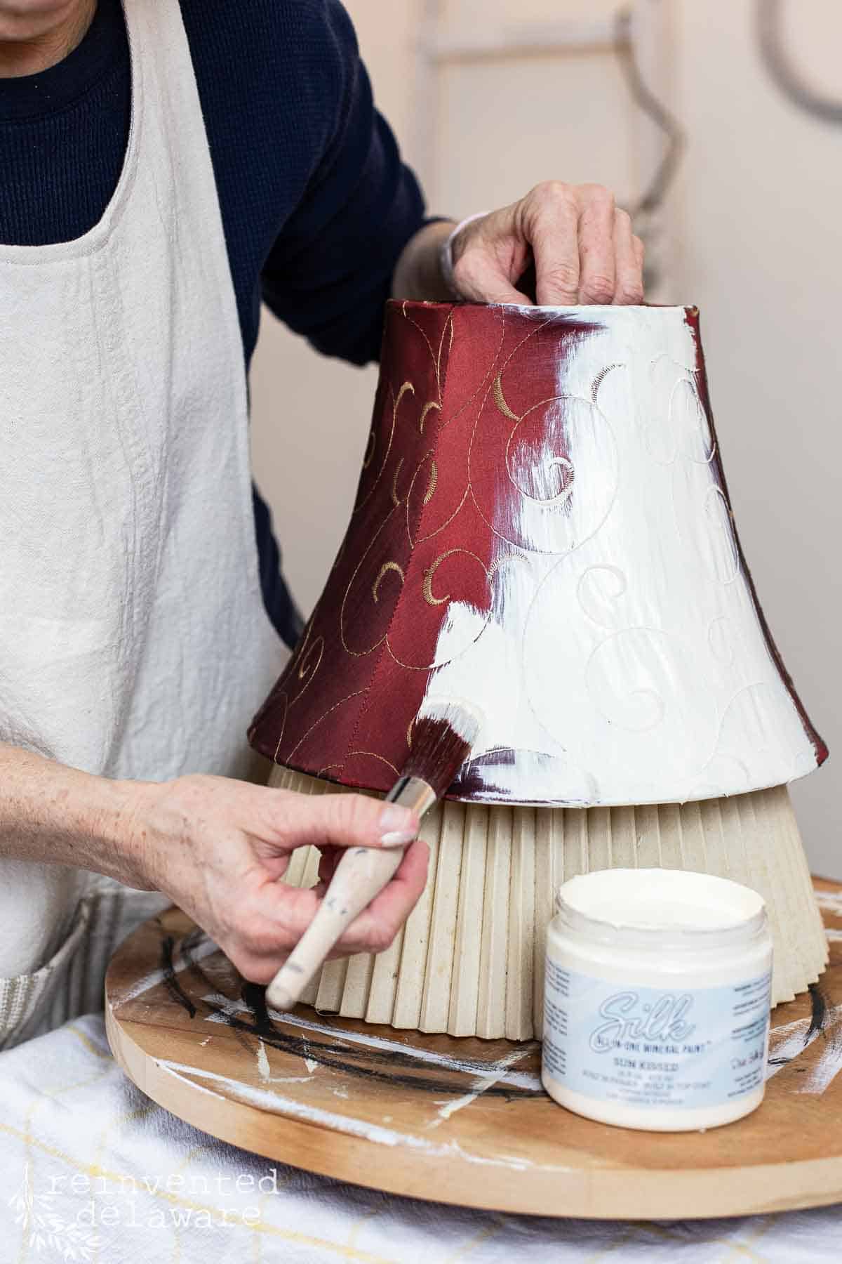 Lady painting an old red lampshade with linen color chalk paint.