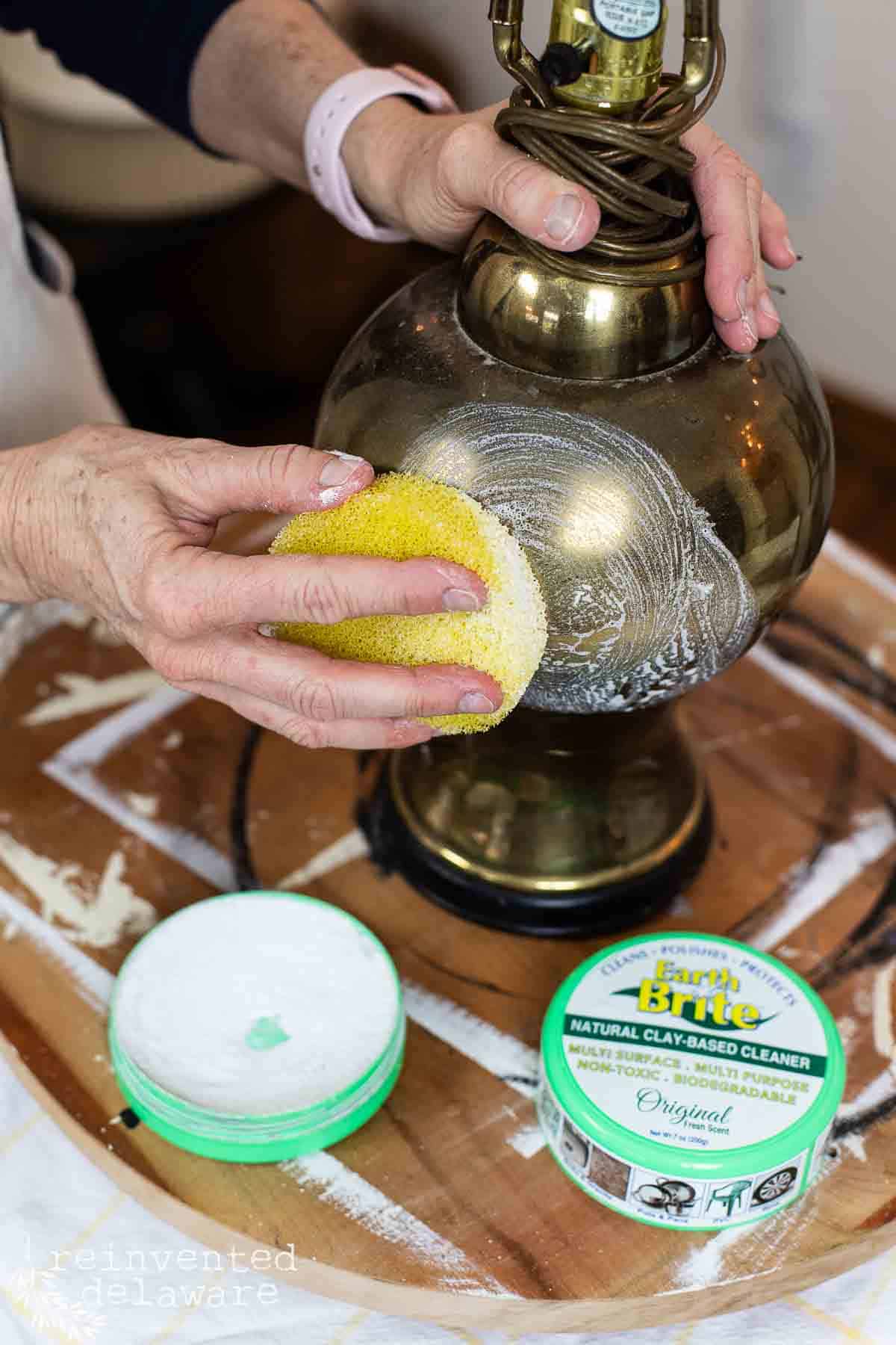 Lady using Earth Brite to polish an old brass lamp that is very tarnished.