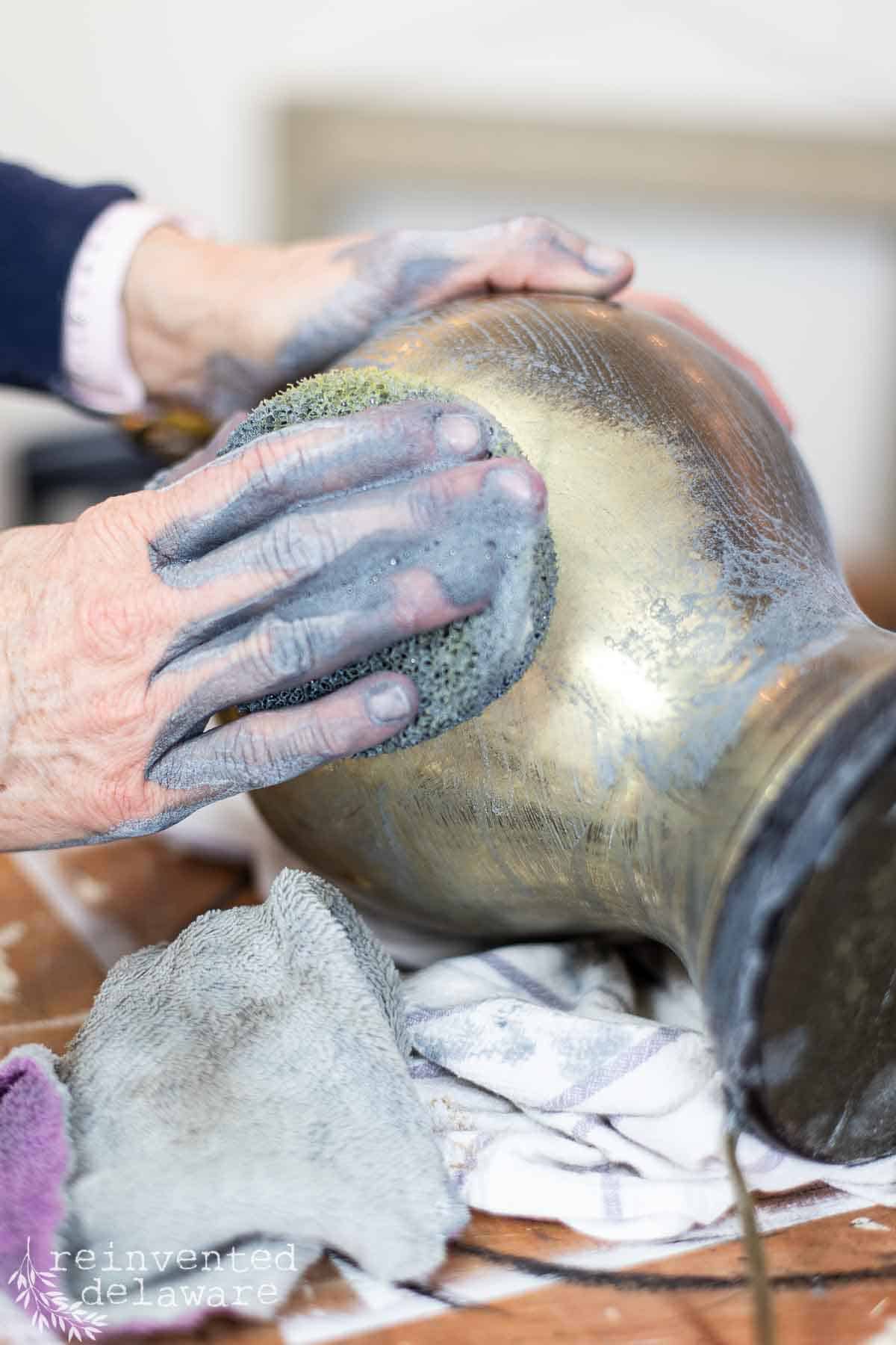 Lady using Earth Brite cleaner to clean an outdated lamp that is brass and dull.