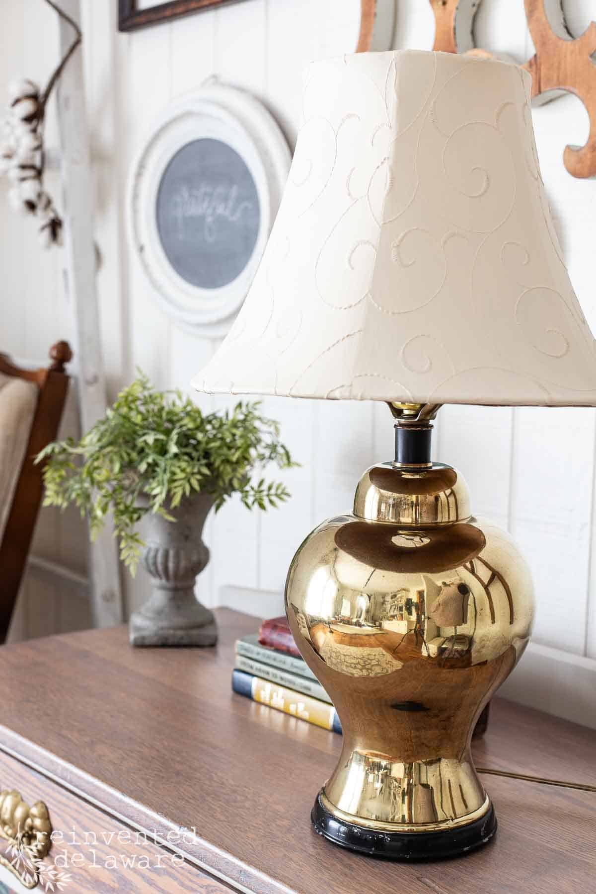 Mid century brass lamp from a thrift store that is polished to a shine and the lampshade has been painted white.