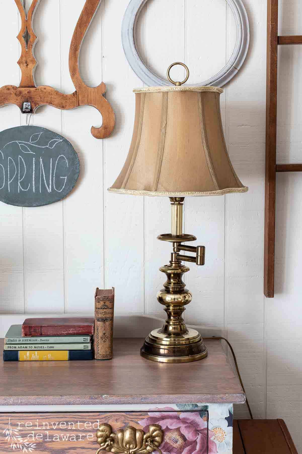 Thrift store brass lamp that has been polished and the lampshade clean sitting on top of an antique washstand.