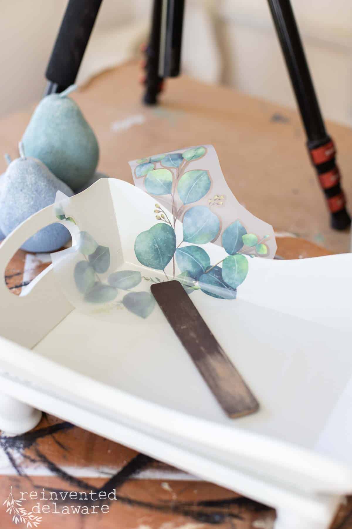 decorative transfer being applied to a thrift store wooden tray that is painted in pale gray