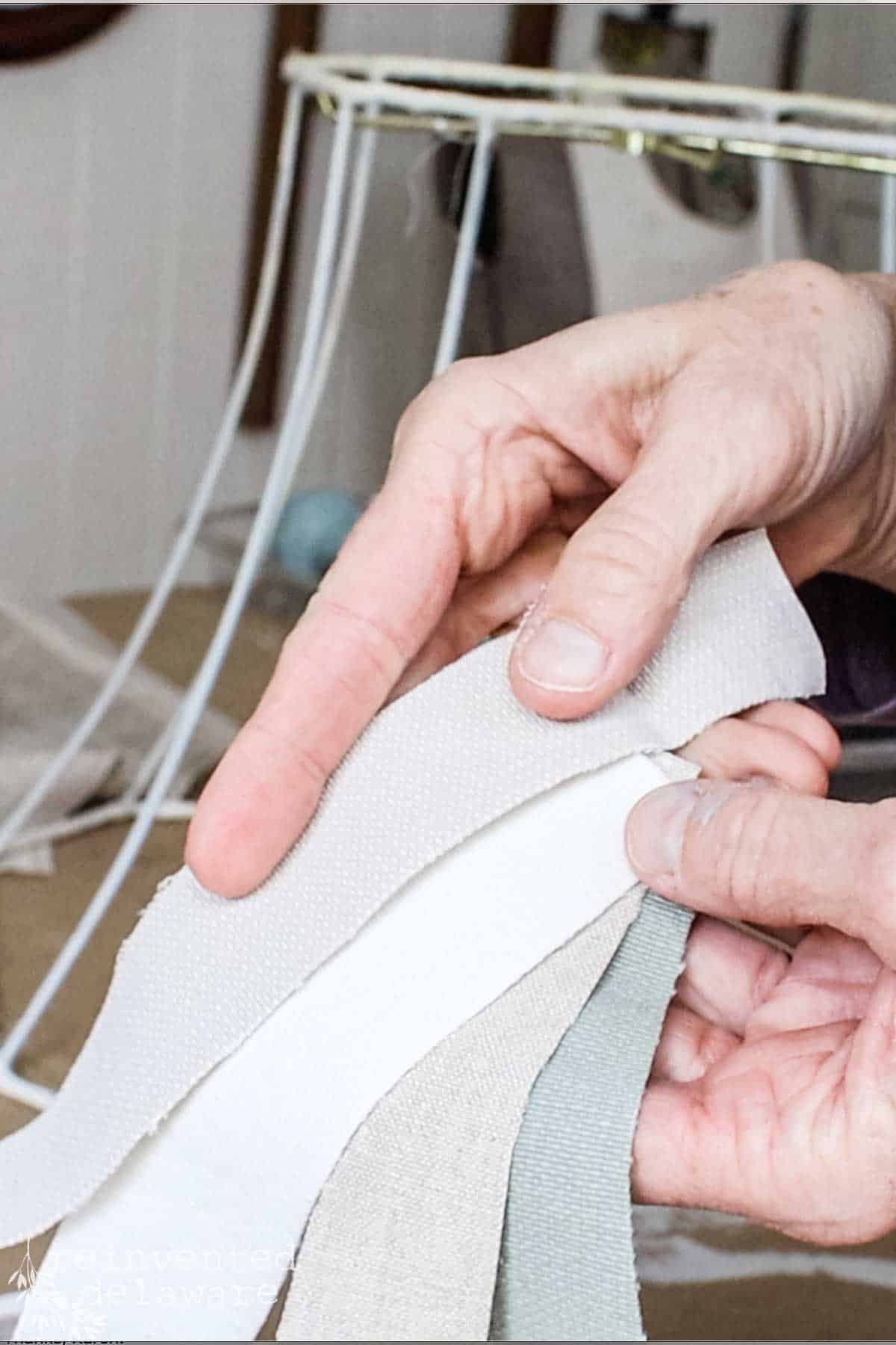 a lady showing scrap fabrics cut into strips for a lampshade makeover project