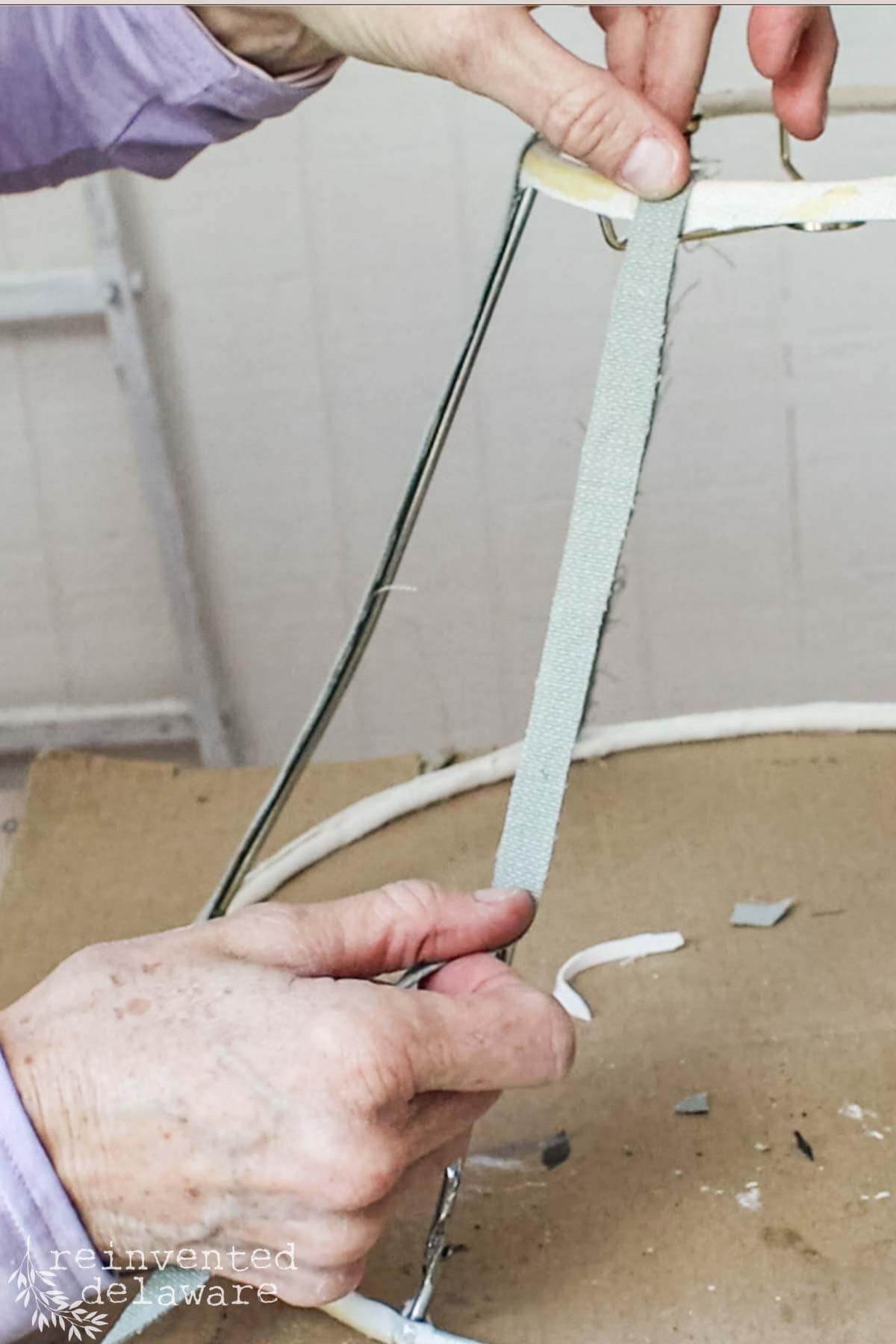 a lady glueing on strips of scrap fabric to a wire lampshade frame