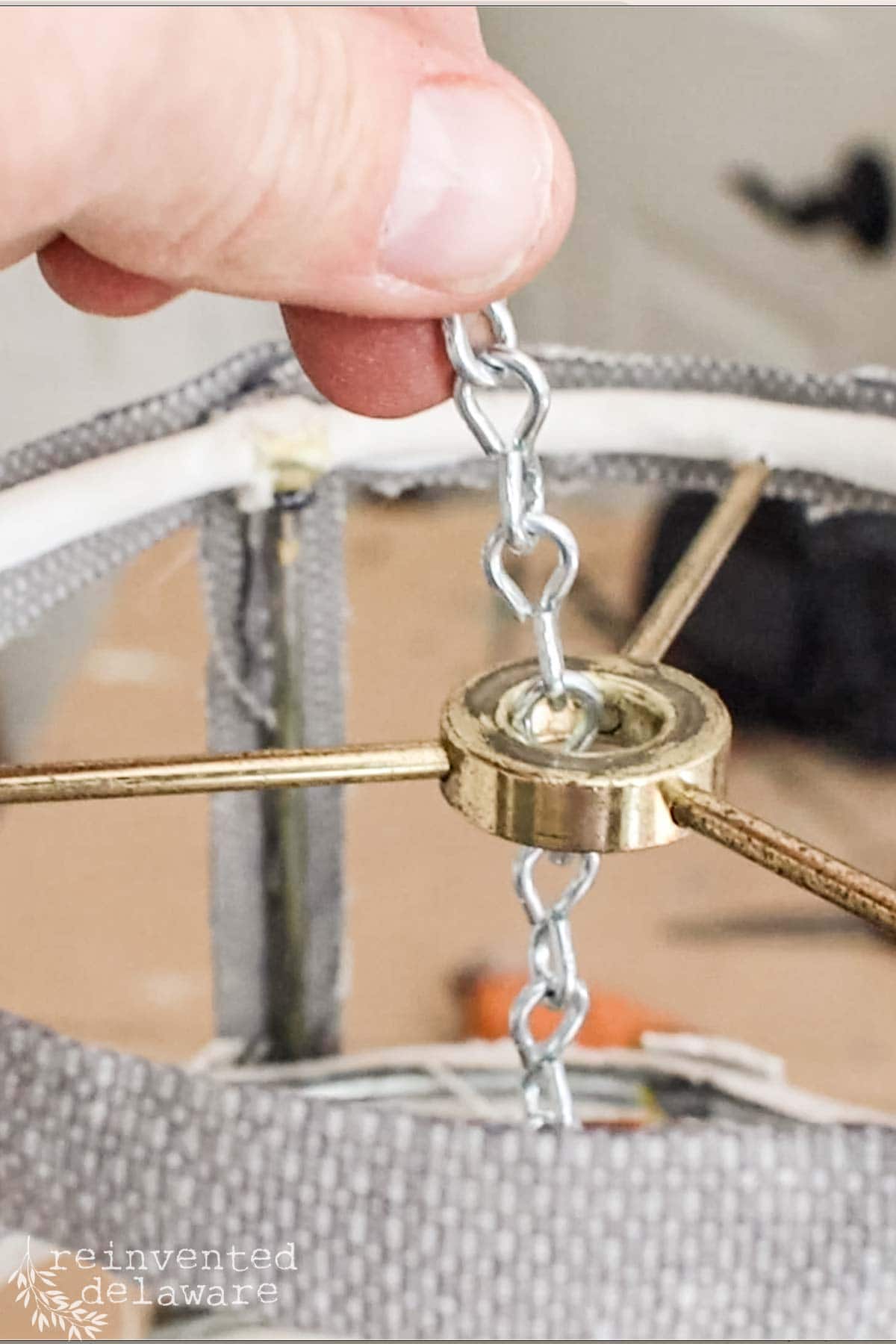 lady attaching chain to a diy lampshade makeover project to make it a hanging light fixture