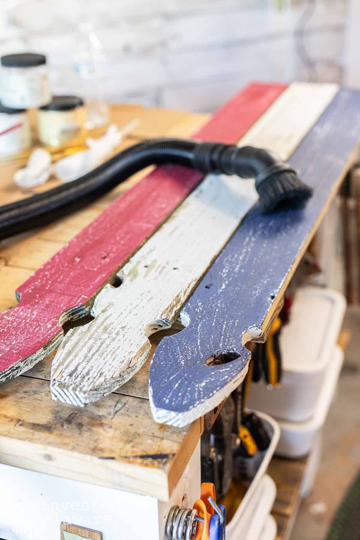 A shop vac hose remvoing the dust from a DIY wooden flag project.