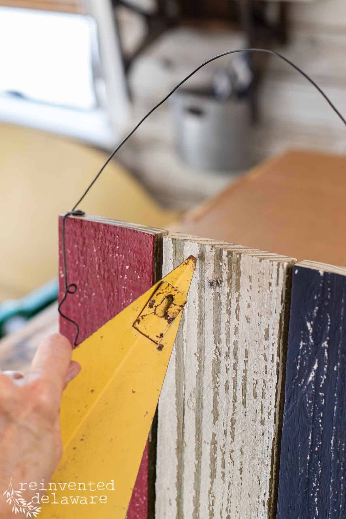 Lady attaching a thrift store metal star to a handmade wooden flag used for patriotic wall art.