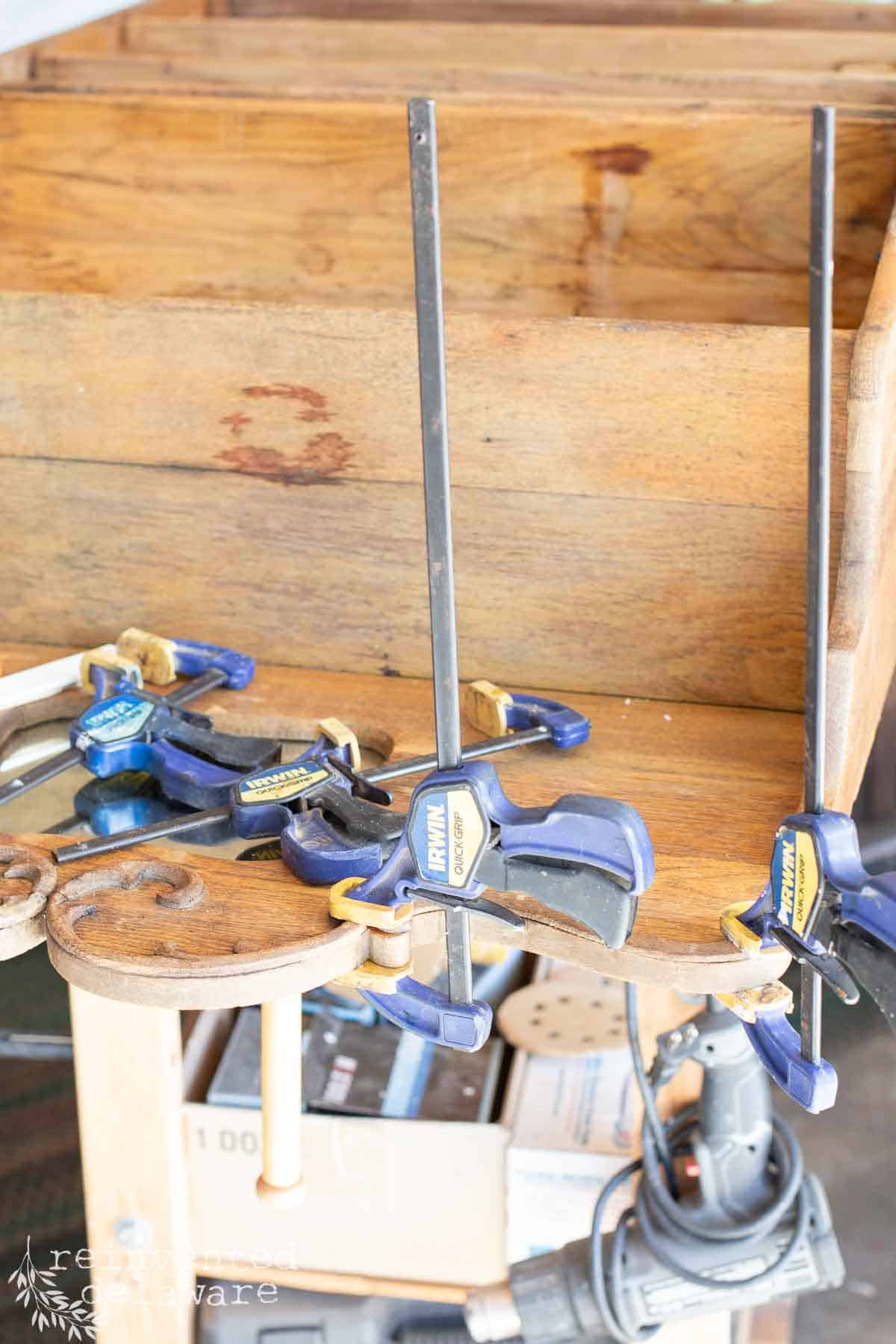 Wood clamps and wood glue on a broken old piece of wood furniture that needed to be repaired.