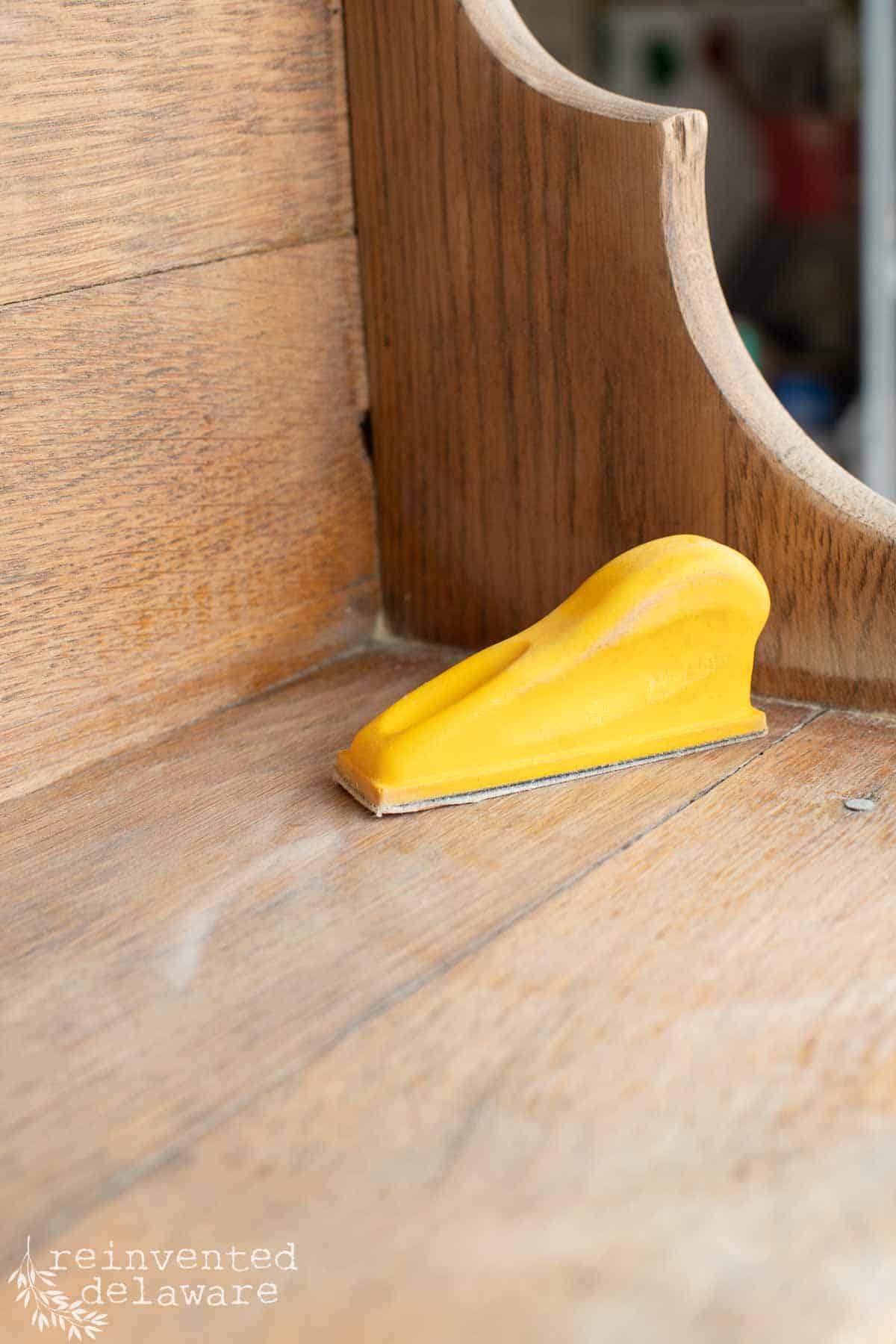 A small yellow hand held sander used for a furniture makeover.