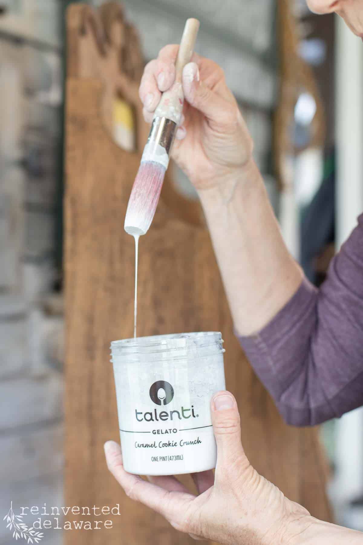 Lady showing thin consistency of watered down milk paint for a whitewashed furniture makeover.