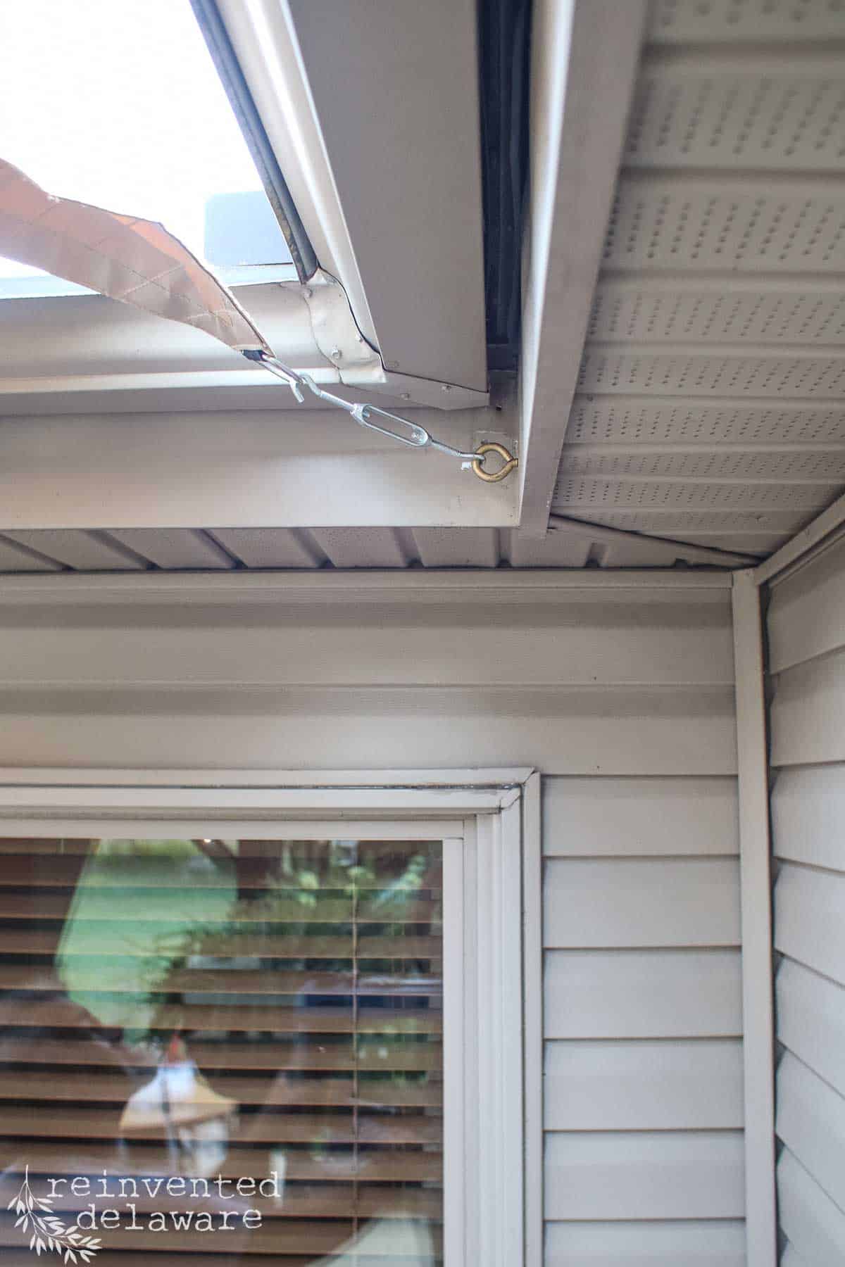 DIY sun shade attached the corner of the exterior area of a patio.