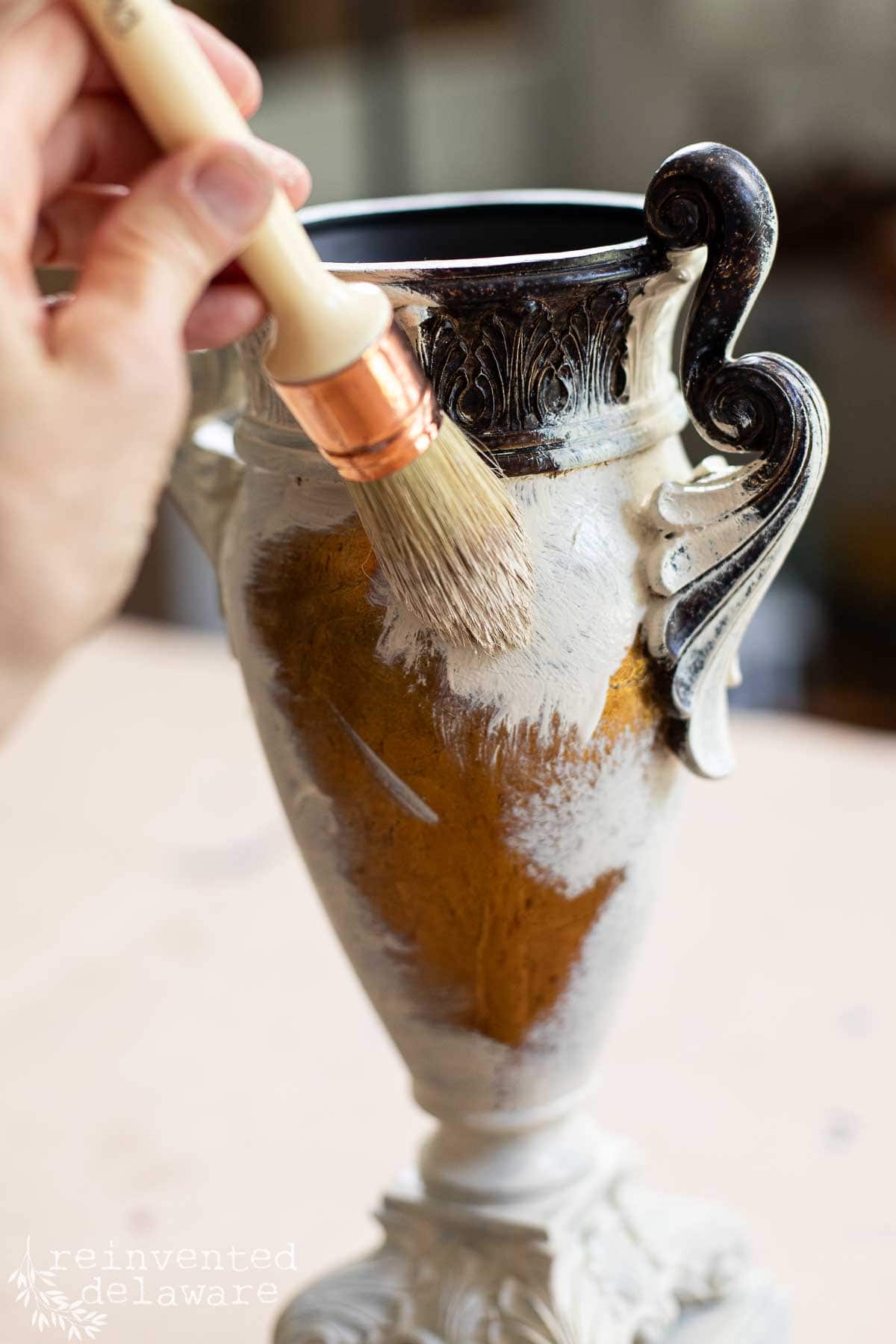 Lady painting an old urn from the thrift store for an upcycle project.