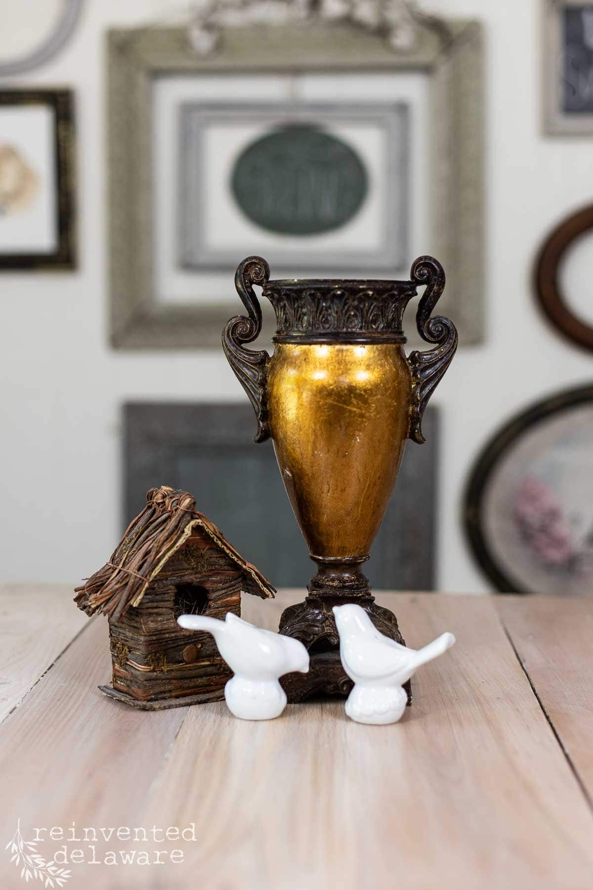 An old thrift store urn that is gold and bronze, a birdhouse and two bird salt and pepper shakers used to upcycle home decor.