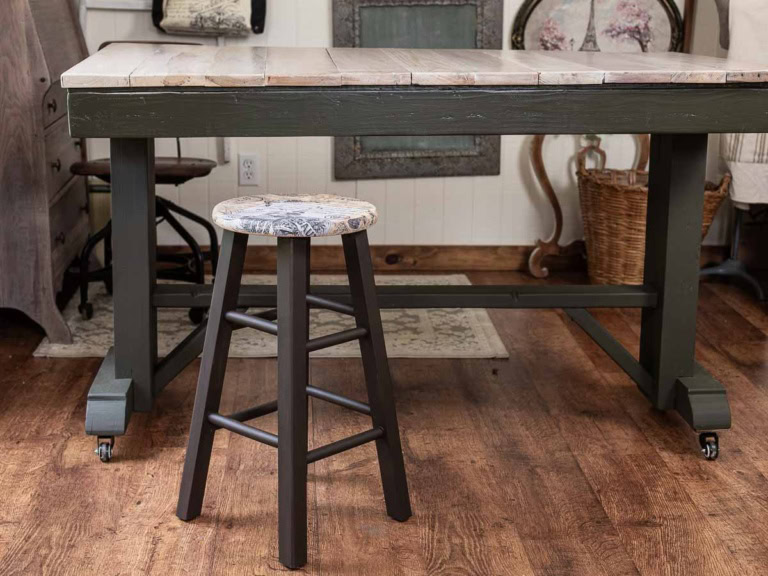 Wooden bar stool makeover with brown chalk paint and a transfer sitting next to a craft table.