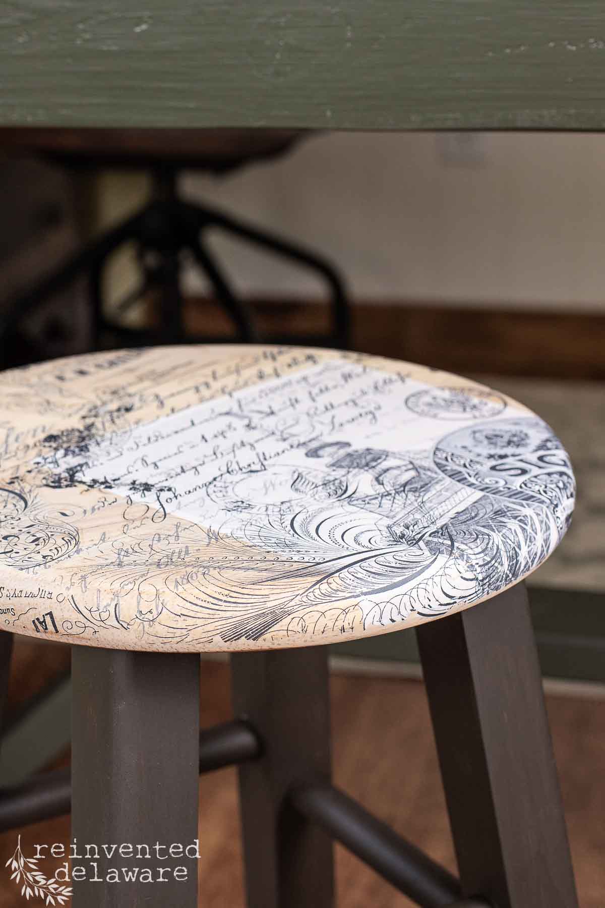 Close up view of a vintage inspired transfer on the seat of a wooden barstool.