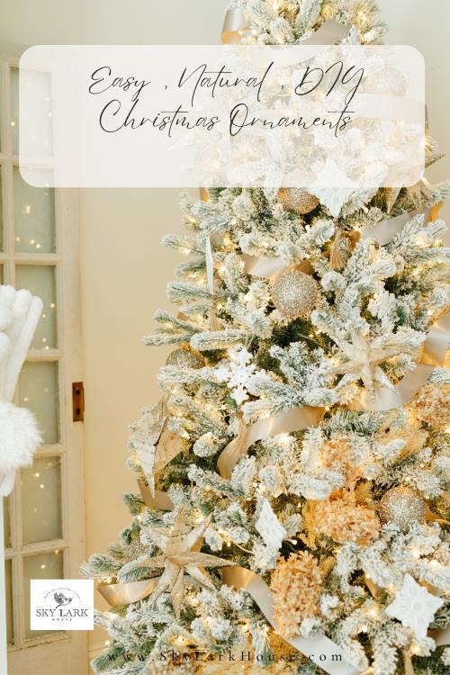A beautifully decorated Christmas tree adorned with snowy branches, gold and white ornaments, and a white ribbon. Soft wintery lighting creates a cozy atmosphere. The text on the image reads "Easy Natural DIY Christmas Ornaments.