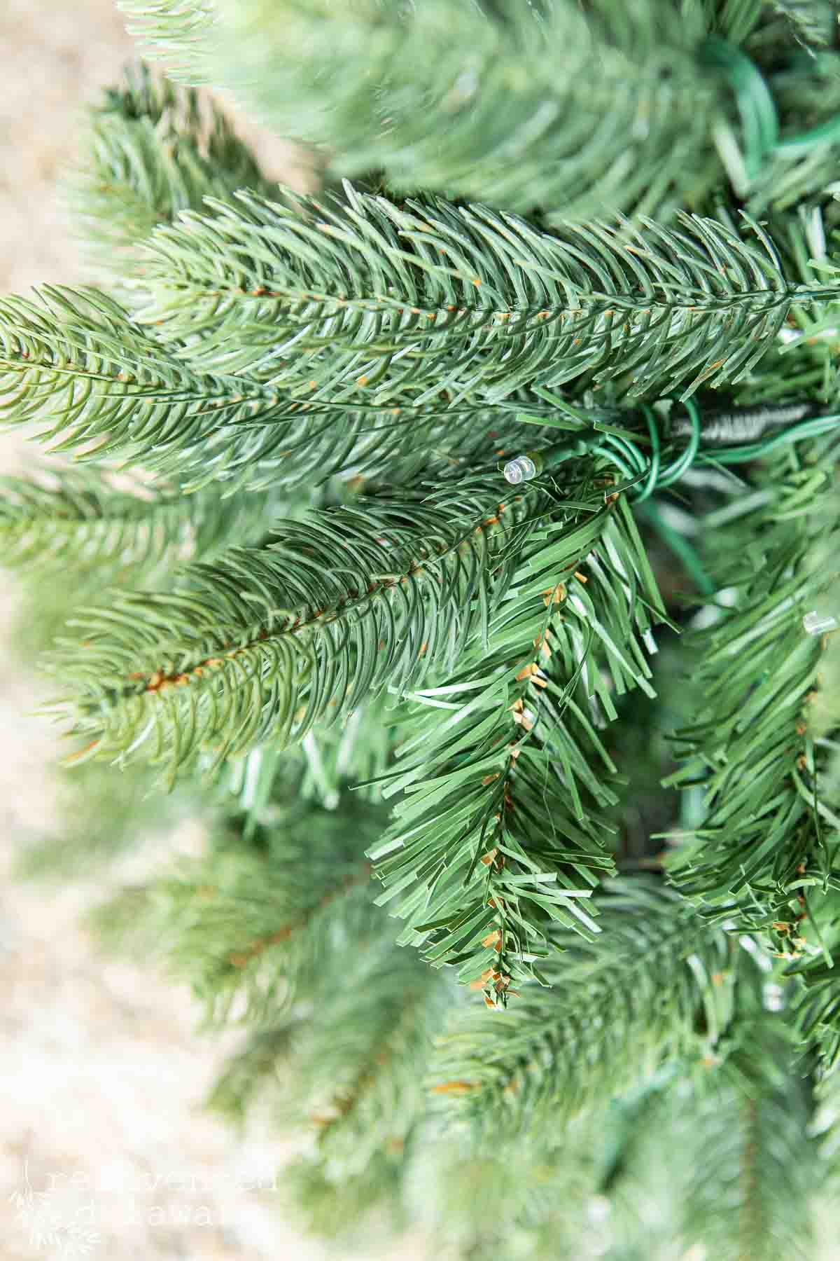 Close-up of a lush, artificial evergreen Christmas tree branch with detailed green needles.