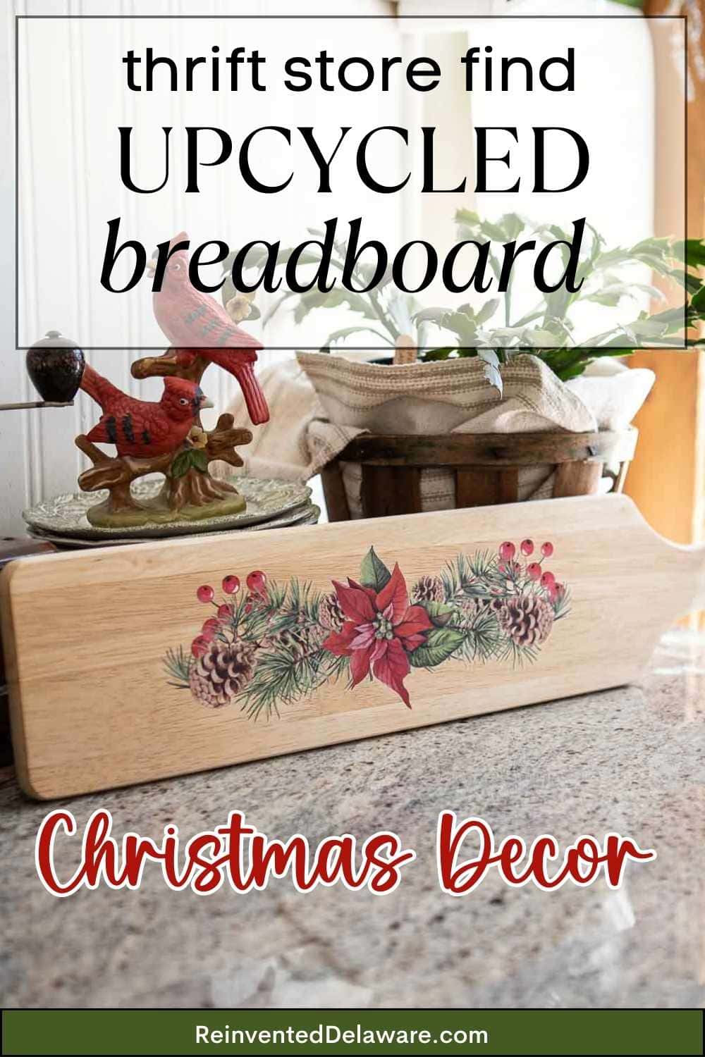 Wooden breadboard with painted Christmas decor, featuring pinecones and poinsettias, placed on a countertop. A small basket with pinecones and a red cardinal figurine are in the background. Text reads, "thrift store find upcycled breadboard Christmas decor.