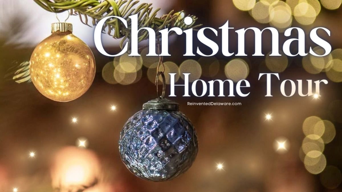 Two Christmas ornaments hang from a branch against a blurred festive background. The text "Christmas Home Tour" is written in large white letters.