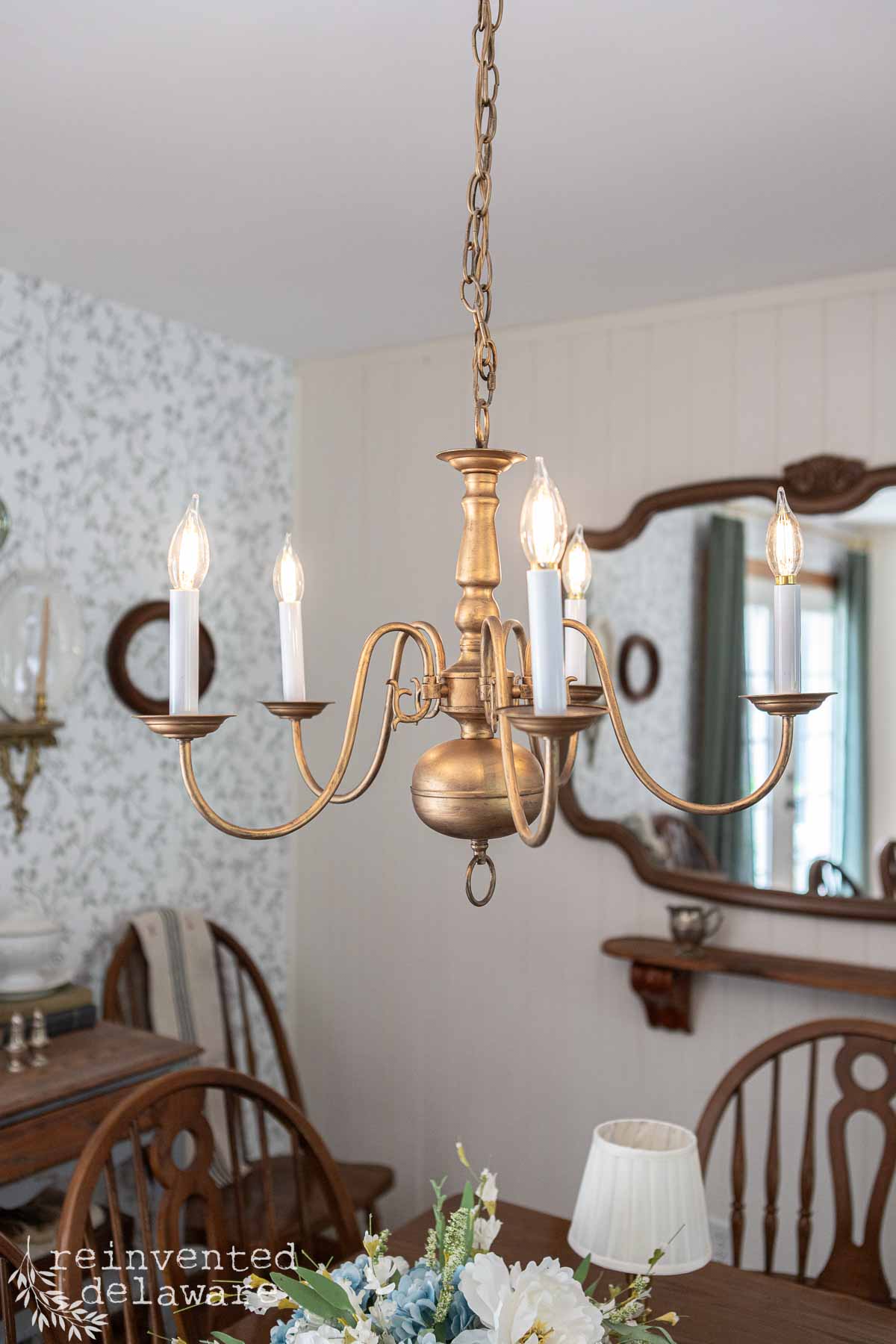 Chandelier with multiple candle-style lights hanging over a dining table.