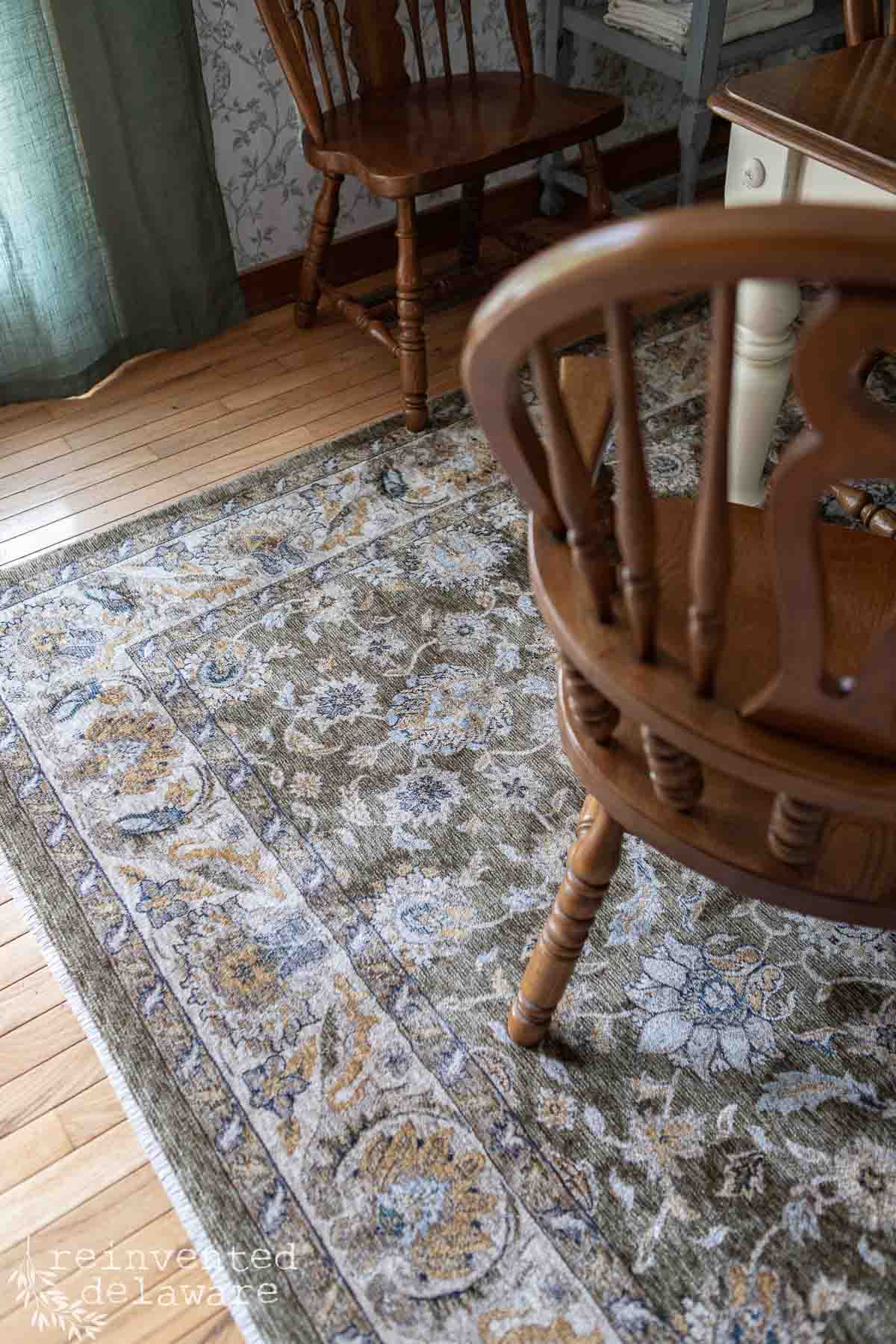 Vintage wooden dining chairs and patterned rug in a cozy, traditional dining room setting.