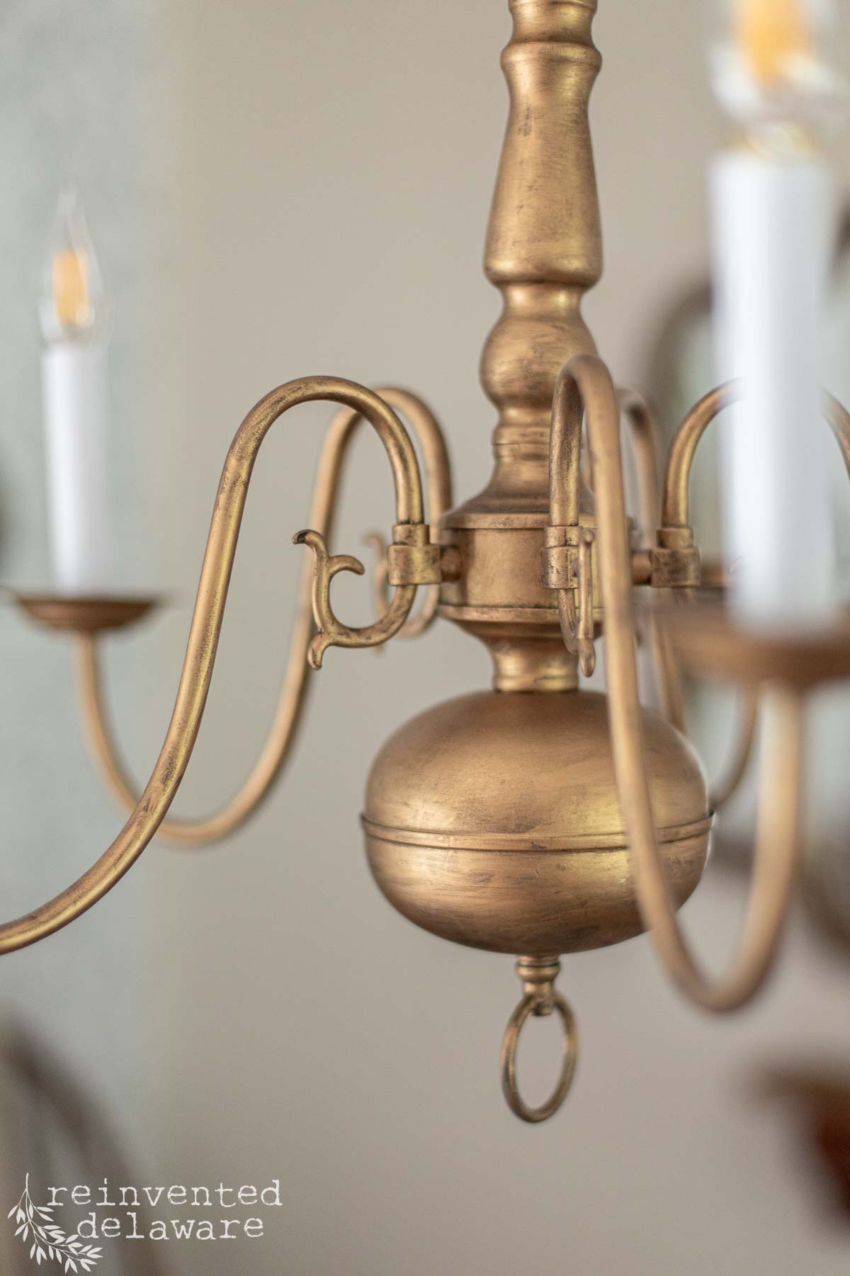 Chandelier with gold finish, candle holders, and intricate detailing.