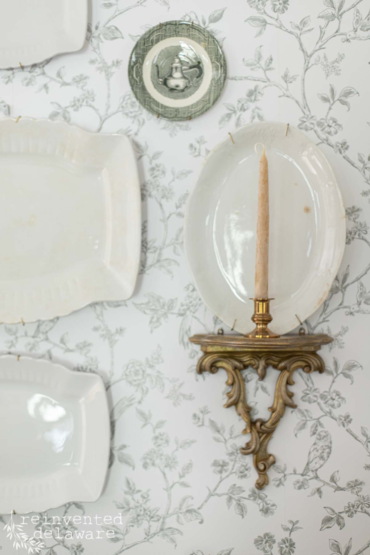 Decorative vintage wall art featuring a candle holder and ornate plates in a cozy, stylish interior.
