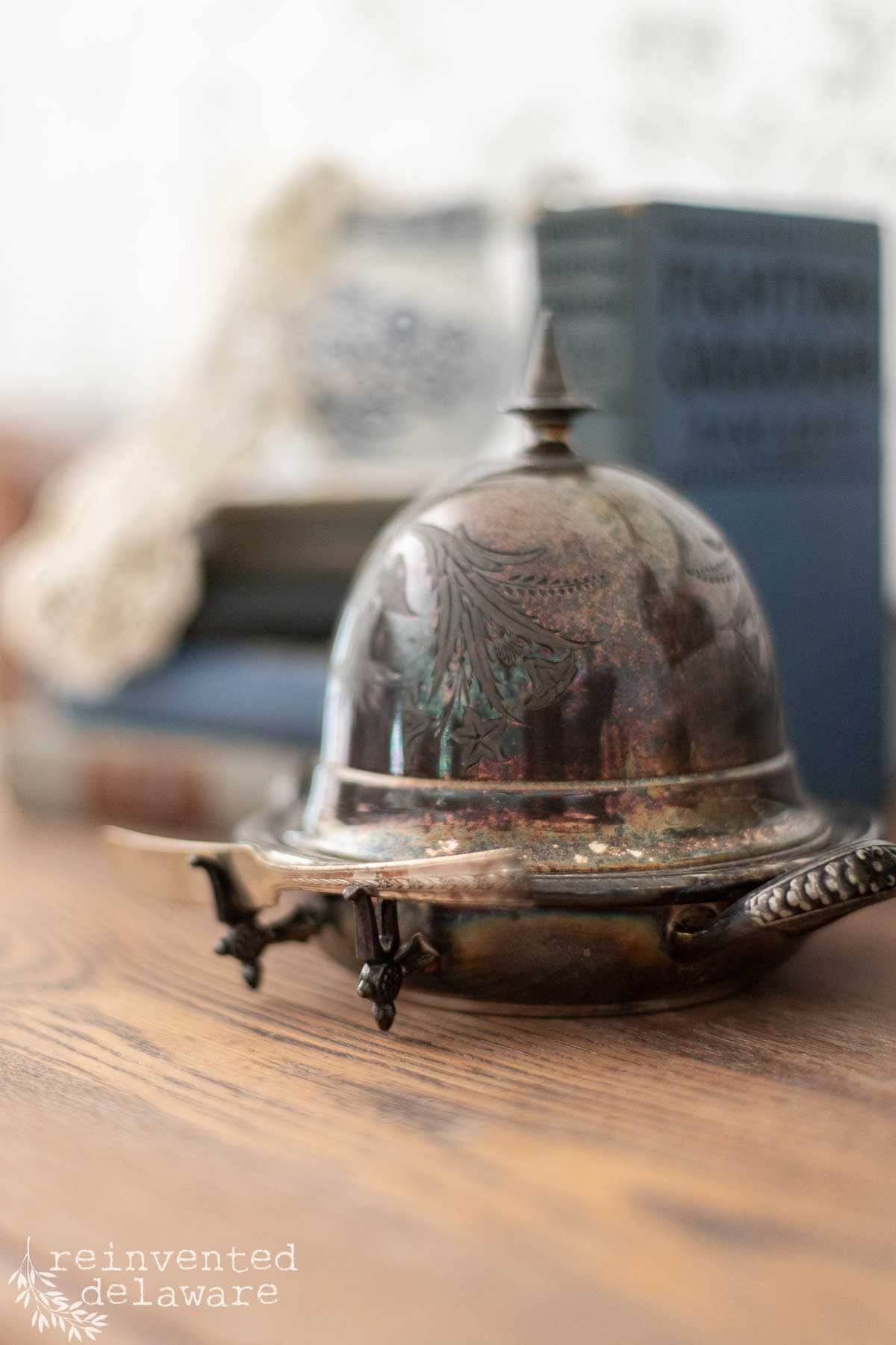Vintage silver cloche dome butter dish on wooden surface.